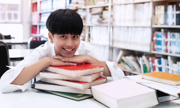 istock Young teenager put her chin on books stacked,between searching data ffor exam,at library,blurry light around 1190848430