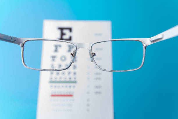 istock Hand-held White glasses, view of the Snellen chart. Blue background 1190848931