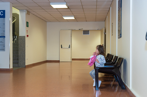 side view of a little girl sitting down on a chair in a waiting room
