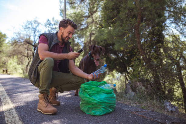 istock Young volunteer man is sorting plastic waste via mobile app with his friend in the forest 1190853451