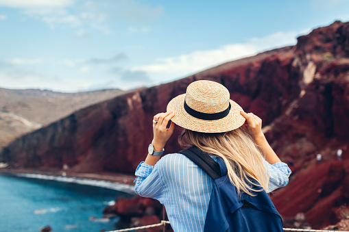 Tourist looking at Red beach landscape from view point in Akrotiri, Santorini island, Greece. Woman traveling the world