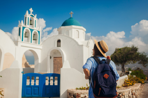Santorini island traveler exploring greek church architecture in Akrotiri. Woman tourist walking during vacation. Traveling around Europe