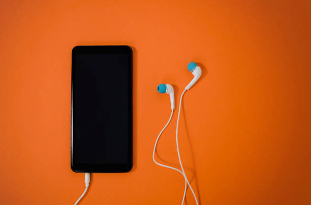 istock Smart phone with earphones on orange background 1190861586