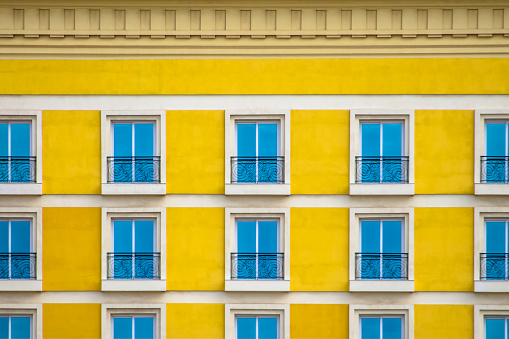 Detailed front view of a facade with windows with balconies and yellow wall...