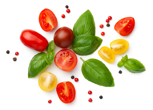 Composition with fresh cherry tomatoes isolated on white background. Red, yellow and brown tomatoes, basil leaves and peppercorns. Top view, flat lay