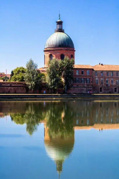 View on the Dôme de la Grave, an emblematic pink brick building in Toulouse (Occitanie, France), and its reflection on the waters of the Garonne river.