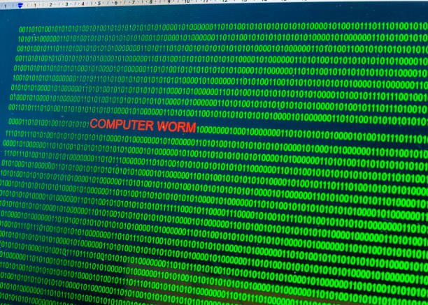 istock Red inscription Computer worm in malicious computer code written by a hacker. Picture of a computer screen with a dangerous program code. 1190869275