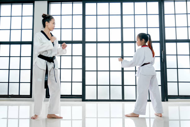 el profesor de taekwondo y el estudiante muestran la acción de diferentes posturas en la sala con ventanas de cristal - martial arts women tae kwon do black belt fotografías e imágenes de stock