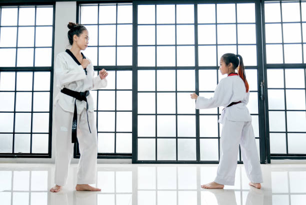 taekwondo professor e aluno mostram ação de diferentes posturas na sala com janelas de vidro - martial arts women tae kwon do black belt - fotografias e filmes do acervo