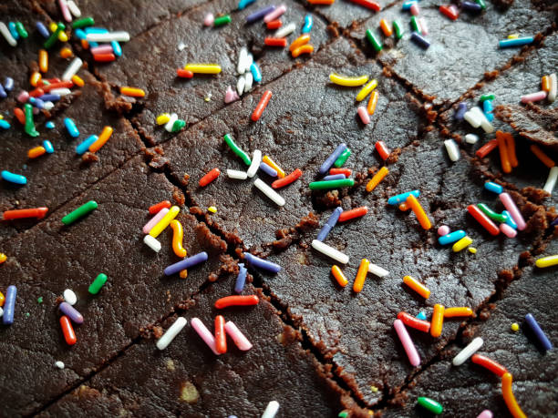 Slightly angled top down close up photo of cut, but not separated pieces of Chocolate Biscuit Sprinkle Cakes laid on a flat surface stock photo