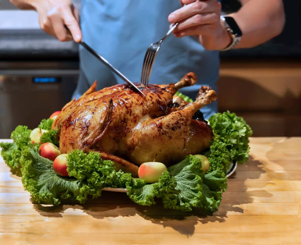 istock Hands cutting roast capon (turkey,chicken) on the kitchen table. 1190877644