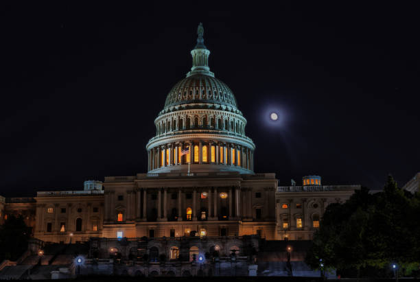 US Capitol shot at night and processed in HDR.  Glowing dome with moon to right.