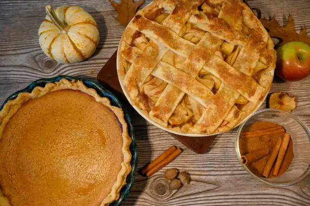 Apple pie and pumpkin pie shown on a wooden table for the holidays