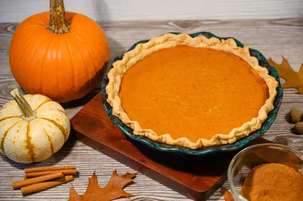 Pumpkin pie  shown with real pumpkins on a wooden table