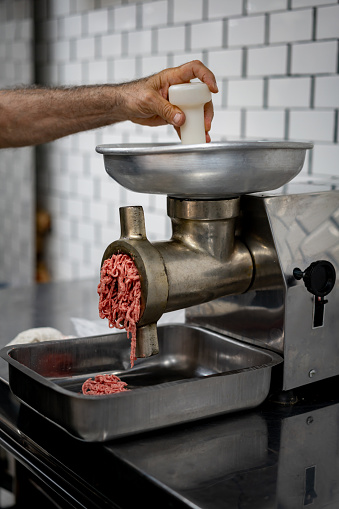 Unrecognizable man grinding meat at the butcher's shop - Retail concepts