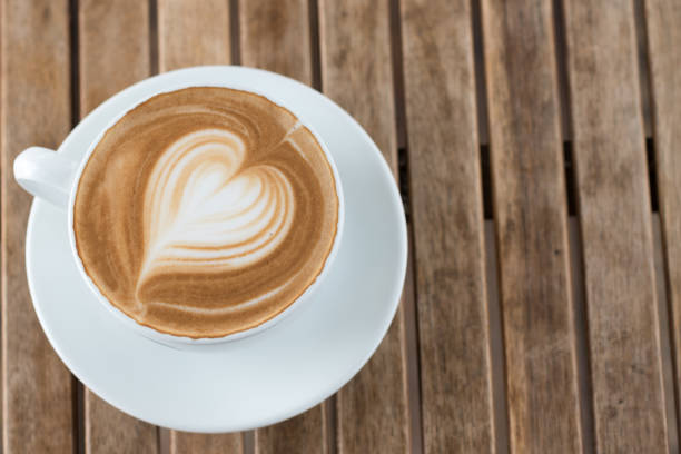 istock A cup of hot coffee with milk foam heart shape on a rustic table. 1190888120
