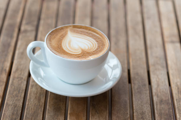 istock A cup of hot coffee with milk foam heart shape on a rustic table. 1190888121