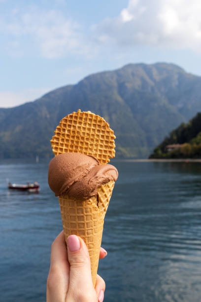 istock Ice cream cone in hand with lake at background 1190895309