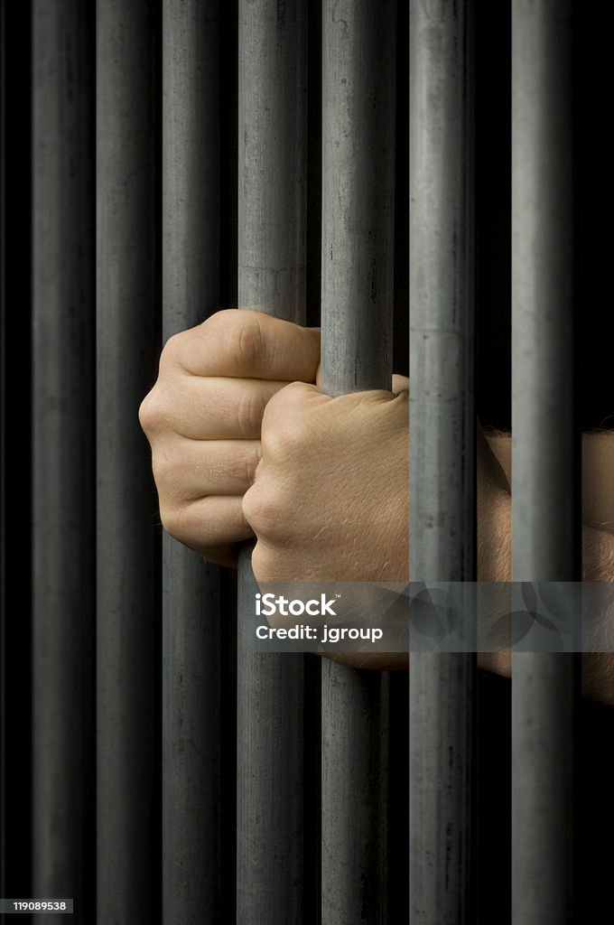 Behind Bars Two hands clutching prison bars Prison Bars Stock Photo