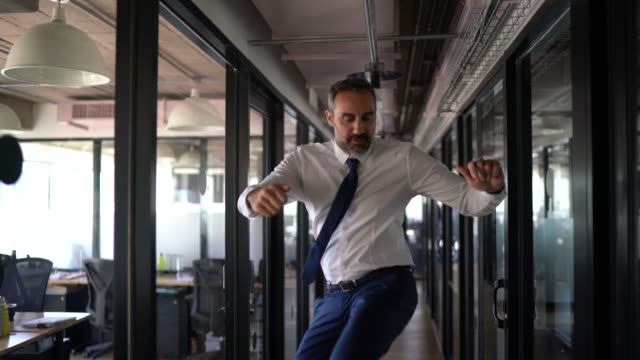 Happy and confident businessman dancing in the office