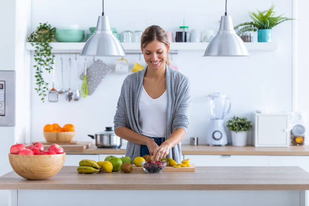 istock Pretty young woman preparing fruit drink in the kitchen at home. 1190896785