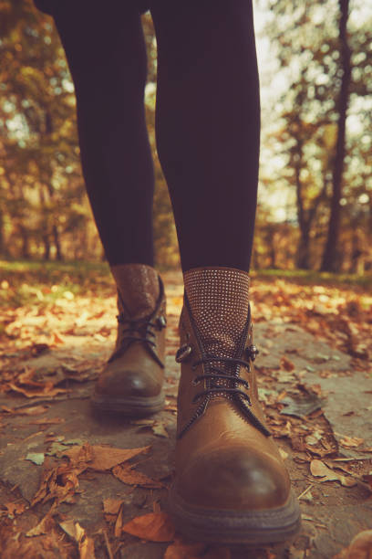 istock Women's legs standing in autumn leaves. 1190897773