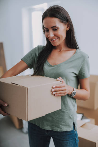 istock Smiling nice lady is looking at cardboard box 1190902024
