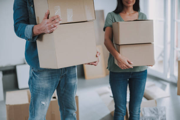istock Young couple carrying cardboard boxes in room 1190902165