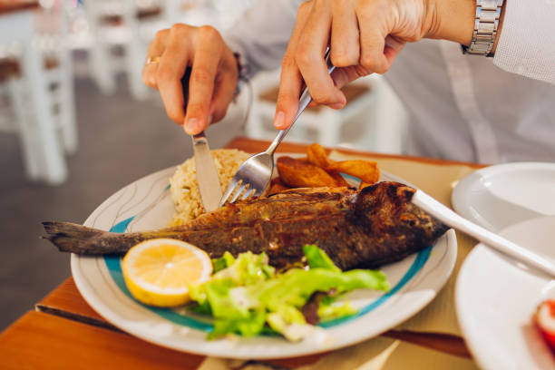 istock Man eats fish with vegetables in outdoors restaurant. Fresh seafood dinner served for one. 1190904116