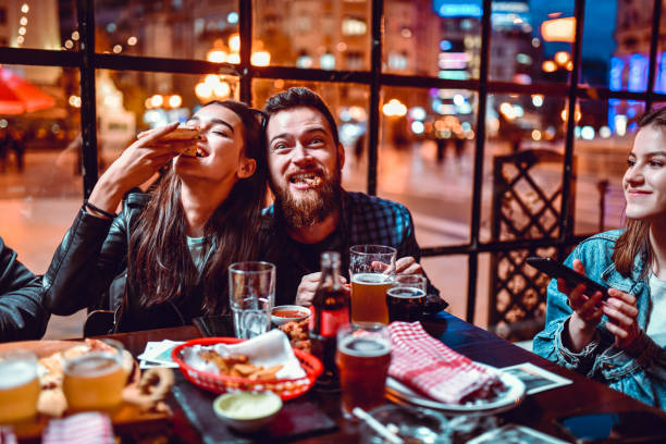 urocza para ciesząc się kolacją z przyjaciółmi - eating food biting pizza zdjęcia i obrazy z banku zdjęć