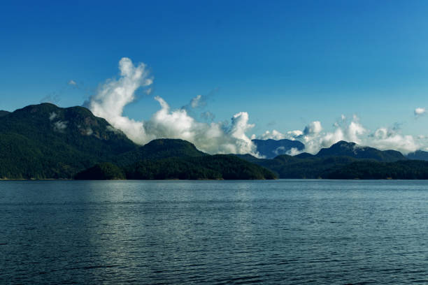 istock White clouds rise above the mountains reflected in the water - Pacific Ocean, BC, Canada 1190904739
