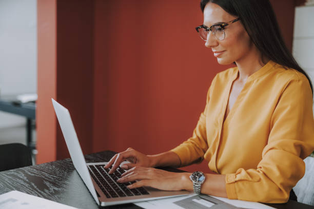 istock Pretty young woman is using laptop in office 1190906784