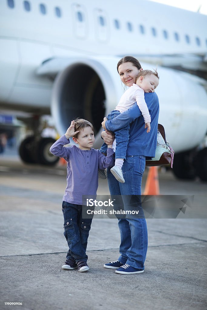 Family travelling Young mother with two kids in front of airplane Adult Stock Photo