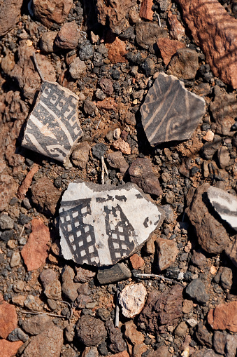 Nearly a thousand years ago natives inhabited the lower elevations around the San Francisco Peaks of Arizona. In an area so dry it would seem impossible to live, they built pueblos, harvested rainwater, grew crops and raised families. Today the remnants of their villages dot the landscape along with other artifacts. Decorated pottery such as the shard shown in the picture was likely not produced in the area where the shard was found. This type of pottery was brought in for trading purposes by people from nearby tribes. It is unlawful to remove shards from an archeological site. They may be examined but must be returned to their original location. These pottery shards were found on South Mesa in Wupatki National Monument near Flagstaff, Arizona, USA.
