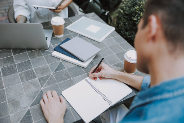 istock Young man is sitting in cafe and writing 1190916707