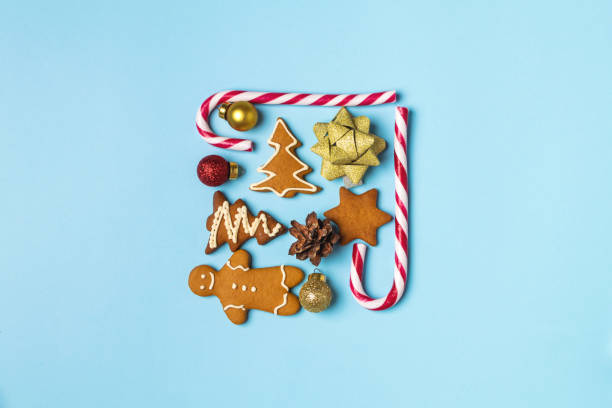 istock Christmas creative concept flat lay, gingerbread, candy cane, bow, pinecone on light blue background 1190919488