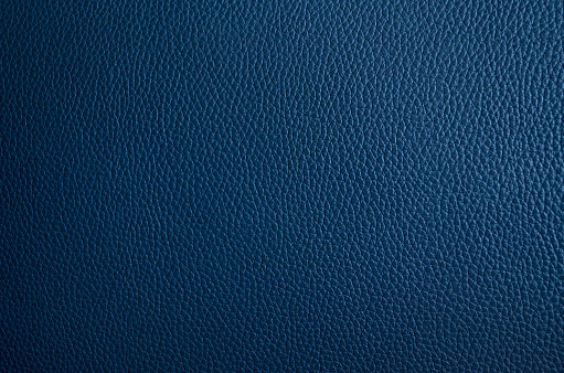 Leather texture close up. Dark blue fashionable background, top view. Stylish wallpaper of navy blue color. Rough surface