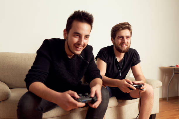 istock Two young males playing video games, having fun, and arguing while sitting on the couch at home 1190924266
