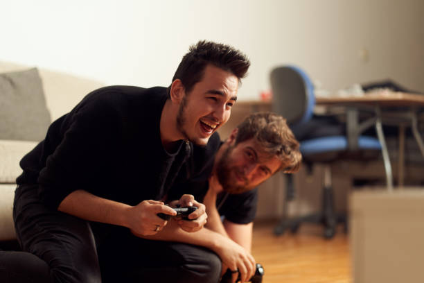 istock Two young males playing video games, having fun, and arguing while sitting on the couch at home 1190924319