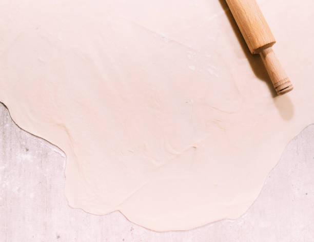 istock Rolled up dough on the table with flour and roller pin top view. 1190925007