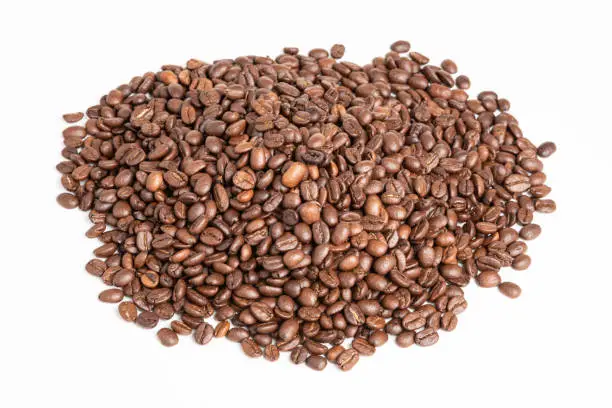 A mound of roasted coffee beans set on a plain white background.