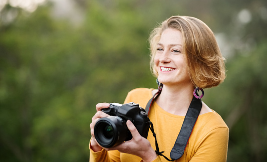 Shot of a female professional photographer enjoying taking pictures with a dslr camera outdoors