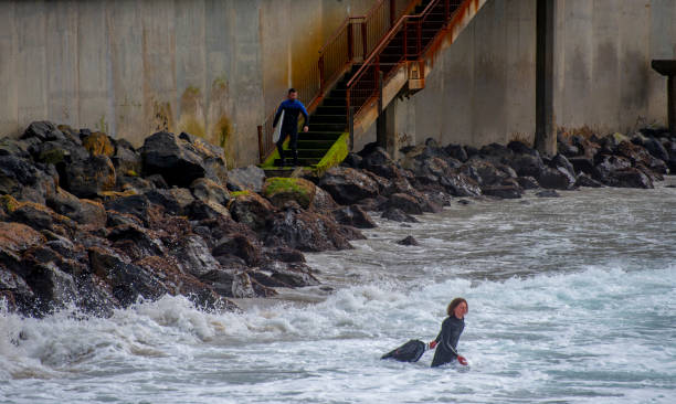 серфер, входящих в воду на пляже в данидин, новая зеландия - 7677 стоковые фото и изображения