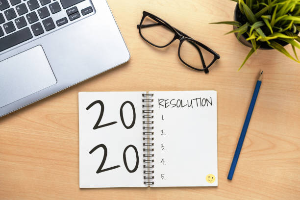 istock New Year Resolution Goal List 2020 - Business office desk with notebook written in handwriting about plan listing of new year goals and resolutions setting. 1190951137