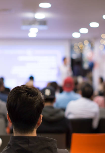 istock Presenter at corporate conference giving speech. Speaker giving lecture to business audience in seminar. Executive manager leading discussion in hall during company training event. 1190954366