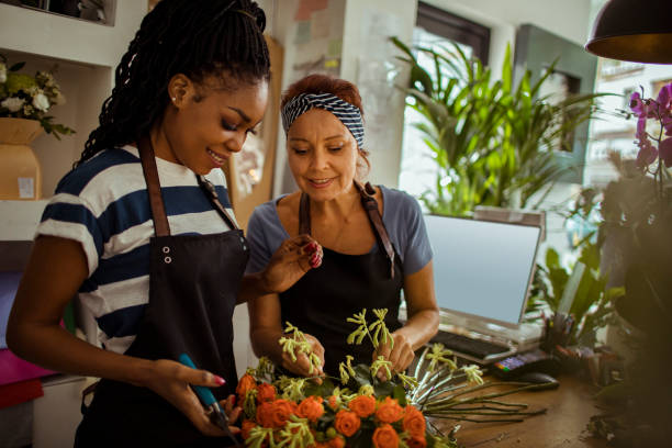 Flower Shop Workers Close up of a flower shop worker teaching the new employee florist stock pictures, royalty-free photos & images