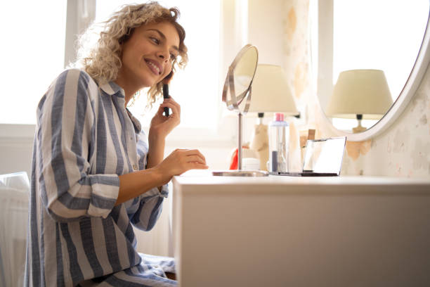 istock Beautiful young woman applying make up 1190959697