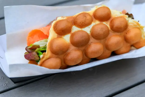 Close up of a ready to eat bubblewrap or bubble waffle smoked salmon sandwich from a fast food restaurant in London, UK