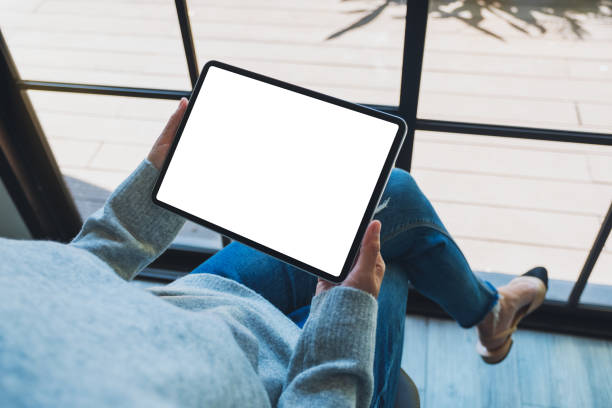 a woman holding black tablet pc with blank white screen Mockup image of a woman holding black tablet pc with blank white screen hand thigh stock pictures, royalty-free photos & images