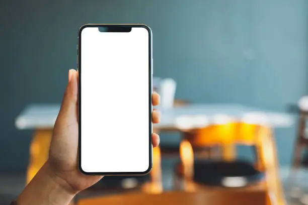 Photo of a hand holding and showing black mobile phone with blank screen in cafe